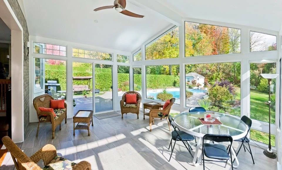 Spacious Florida room with a vaulted ceiling, wicker chairs and windows overlooking a pool